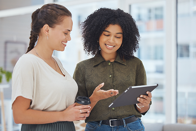 Two coworkers view a tablet